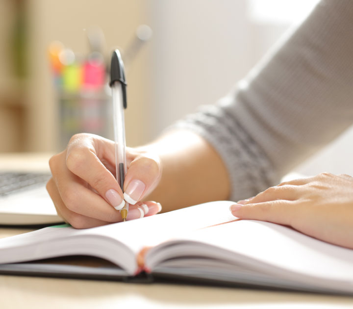 Hand mit Kugelschreiber, die in ein Notizbuch schreibt