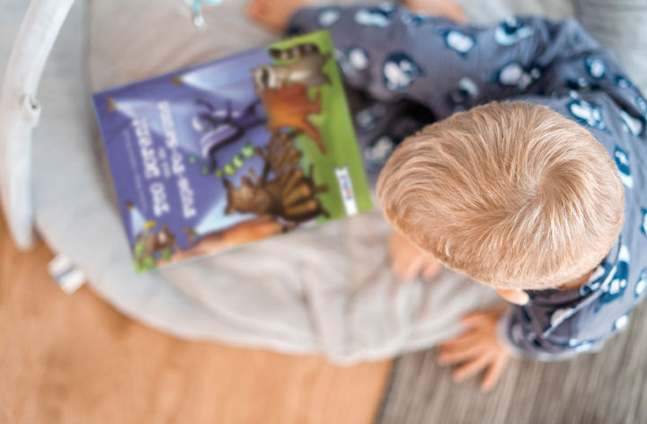 Ein Junge hat das Kinderbuch „Teo Dorant und die Pups-Po-Saune“ von Corinna Wieja im Schoß.