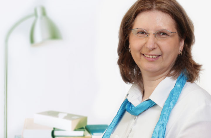 Porträt von Corinna Wieja, im Hintergrund befinden sich eine Lampe und Bücher