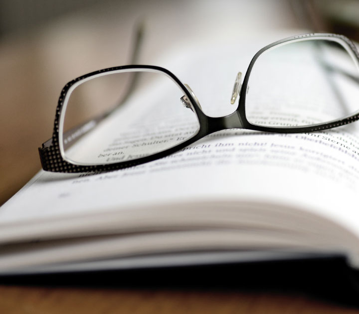 Auf einem aufgeschlagenen Buch liegt eine Brille